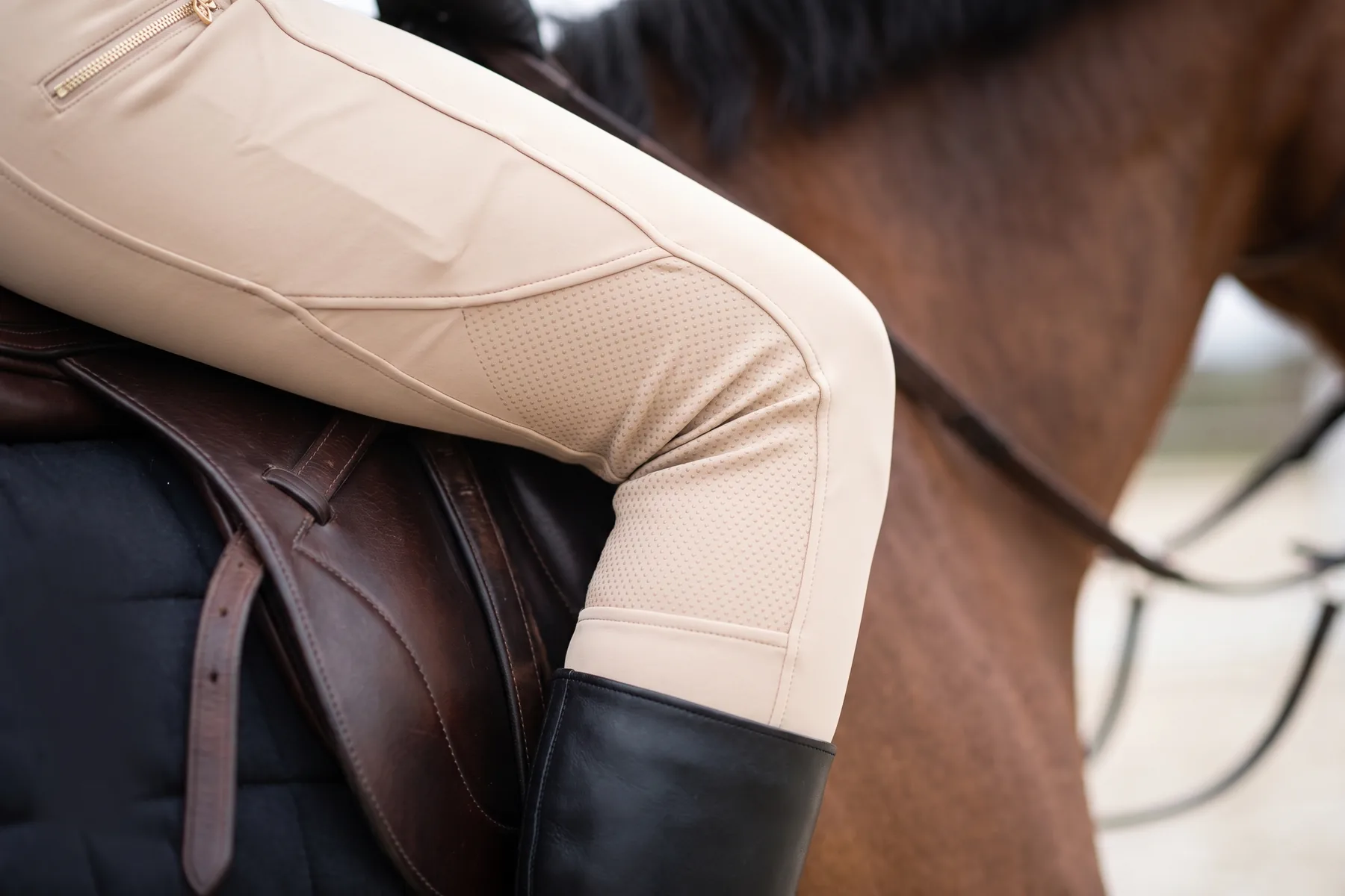 Genou d’une cavalière en selle, grip silicone du pantalon contre le quartier de la selle